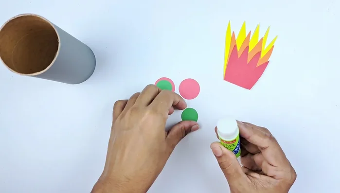 Cut out small circles of green and red paper, layer them (green on red), and glue them together. These will be the rocket's details.