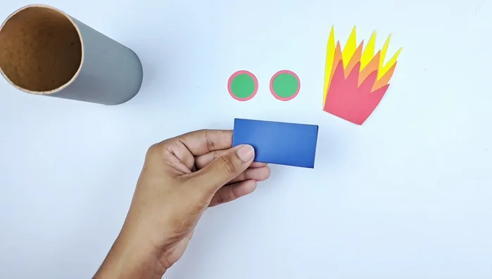 Cut and fold a blue piece of paper to create a triangle shape for the rocket's nose cone.