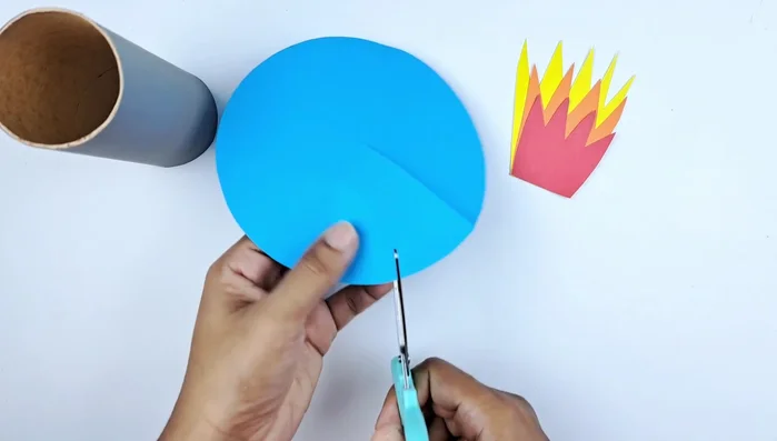 Cut a circle of blue paper to the middle and cut a triangle out. Roll it into a cone shape and glue it together for the rocket's nose cone.