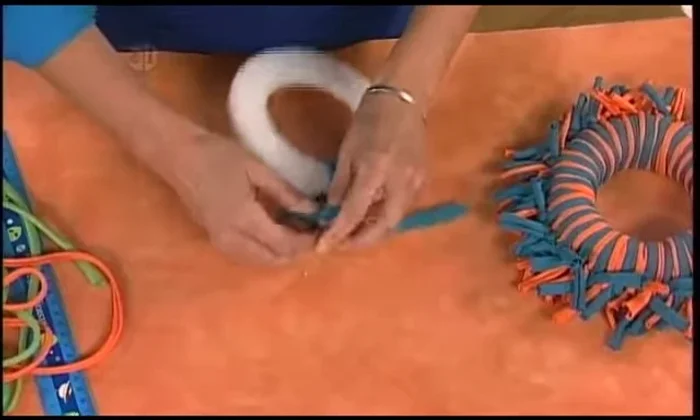 Tie the loops around the styrofoam wreath shape, keeping the knotted section at the top edge. Trim after each loop.