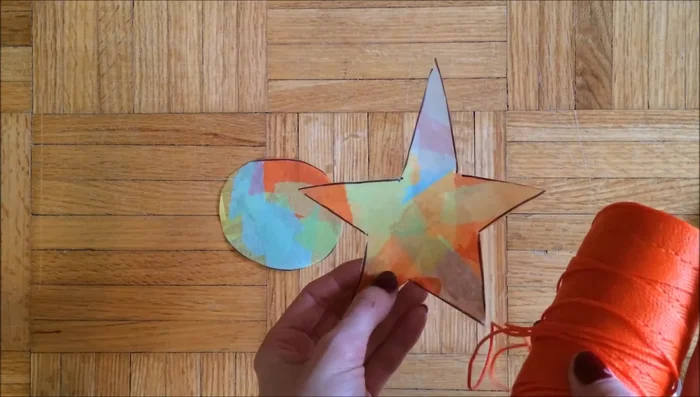 Optional: Add extra details. The example shows cutting out a smaller star from black construction paper, and then gluing it onto a larger, laminated star to create a layered effect.
