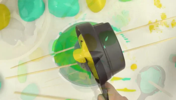 Create a paint-catching tray: Use a small container (like a yogurt cup), punch holes for skewers, and cut the slots.