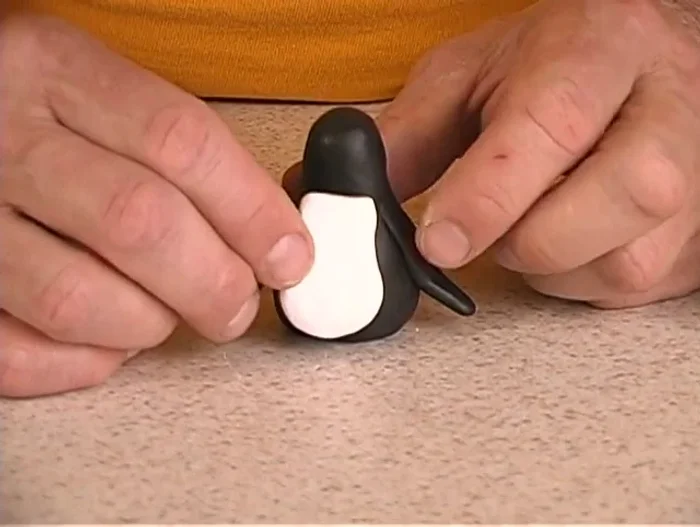Attach the white chest patch to the penguin's body and smooth the edges.