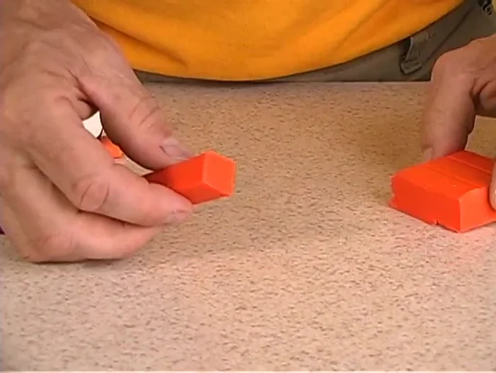 Make two feet by cutting, flattening, and shaping pieces of black clay. Create v-shaped notches on the feet.