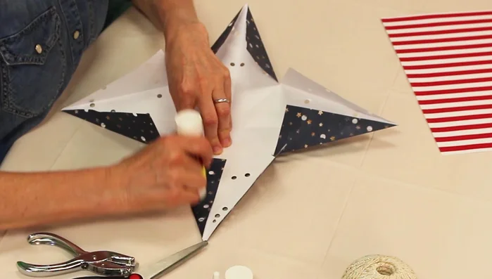 Tie a knot in a string and place it inside a corner of one star's center, securing it with glue. Let dry for one hour.