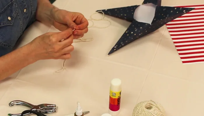 Tie a knot in a string and place it inside a corner of one star's center, securing it with glue. Let dry for one hour.