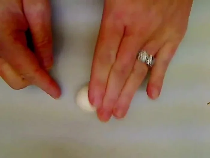 Create the body: Roll a large ball of white cloud clay (about 1.5 inches), pinch the top to form a rounded cone shape resembling a teardrop. Flatten the bottom against the table and pinch up the neckline.