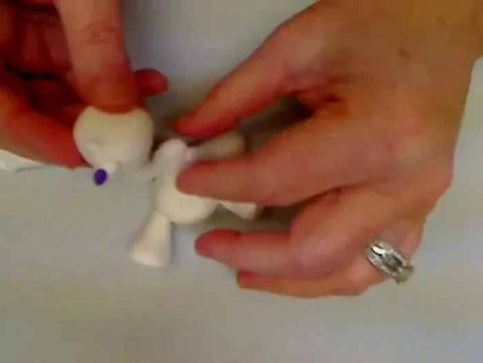 Create ears: Attach two tiny balls of clay to the sides of the head for ears.