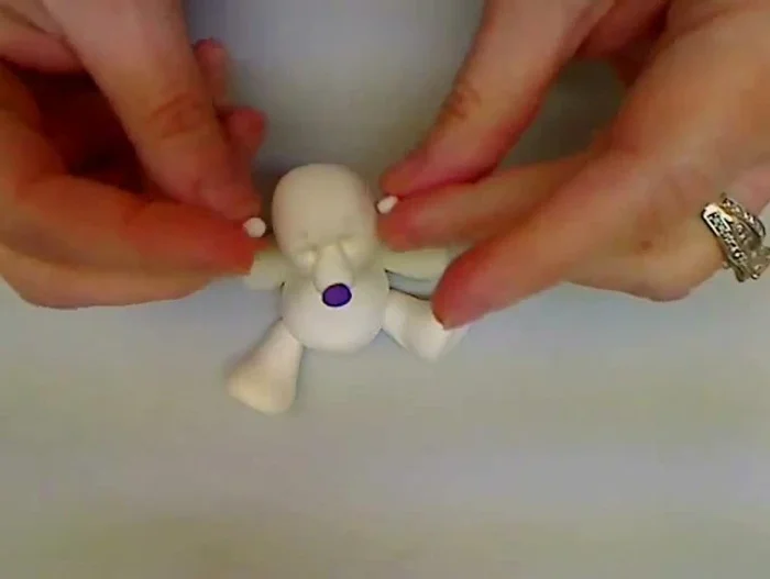 Create ears: Attach two tiny balls of clay to the sides of the head for ears.