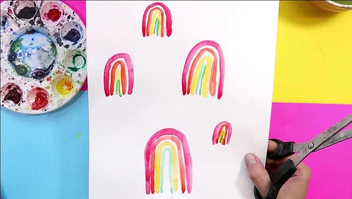 Cut and arrange rainbows: Once dry, cut out the rainbows, leaving a white border. Arrange and glue them onto the background at various angles for an abstract effect.