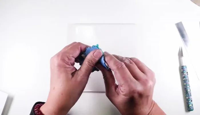 Roll the clay sheet through a pasta machine, perpendicular to the rollers, several times to thin it and blend the colors. Aim for a sheet approximately 4x6 inches and as thin as manageably possible.