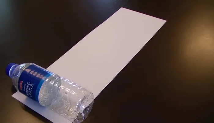 Cut construction paper to match the size of your plastic bottle. Wrap the paper around the bottle and tape or glue the ends.