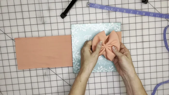 Use your fingers to hold the bow in place while pulling the fabric tight to create a bow shape. Fold the raw ends in neatly.