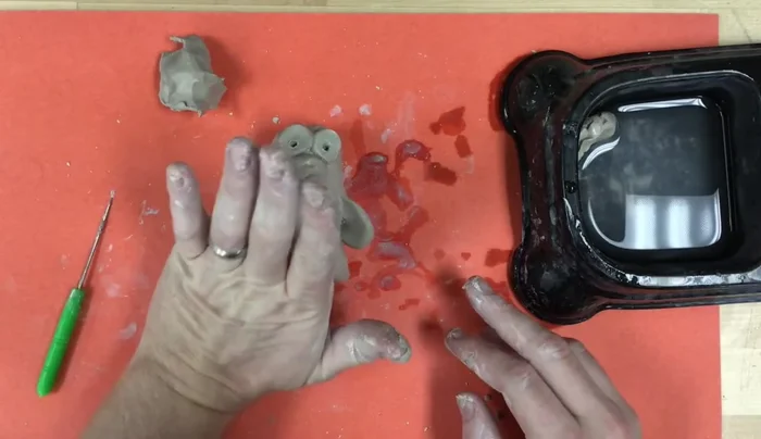 Add feet: Roll small balls, flatten, and cut them into semi-circles. Attach using slip and scratching.