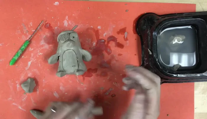 Add a guitar: Demonstrate creating a small guitar using coils and balls of clay, showing how to refine the shape through pinching, pressing, and scratching.