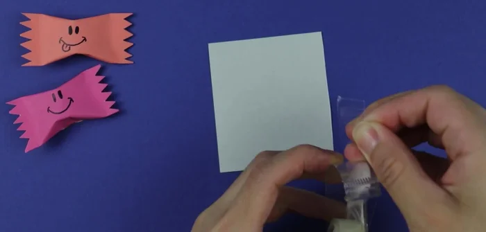 Apply adhesive: Use double-sided tape across the entire sheet of paper. (Glue stick is an alternative, but double-sided tape avoids drying time and candy contact.)