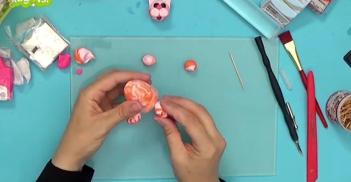 Attach paws and tail: Attach the paws to the body. Combine orange and pink clay for the tail, roll it into a snake-like shape, and attach it to the body using a toothpick.