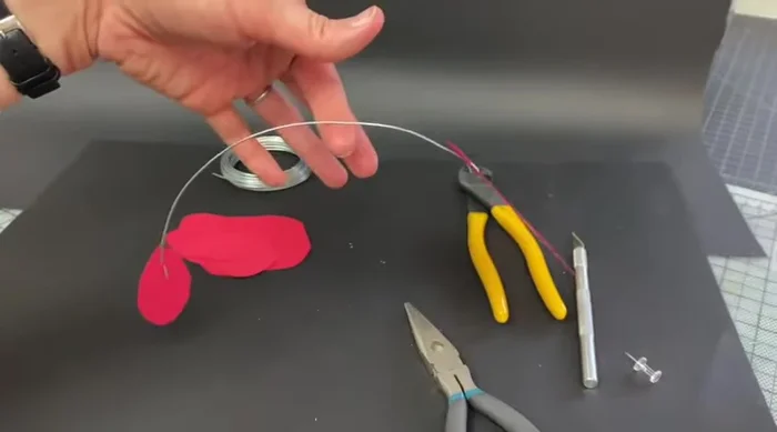 Find the balance point of the wire connecting the two cardstock pieces. Crimp the wire at this point to create a loop.