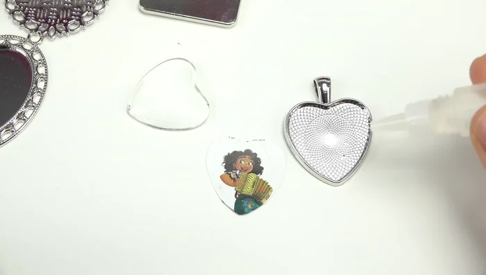 Apply glue to the back of the glass gem and place it on top of the image, pressing gently to secure.