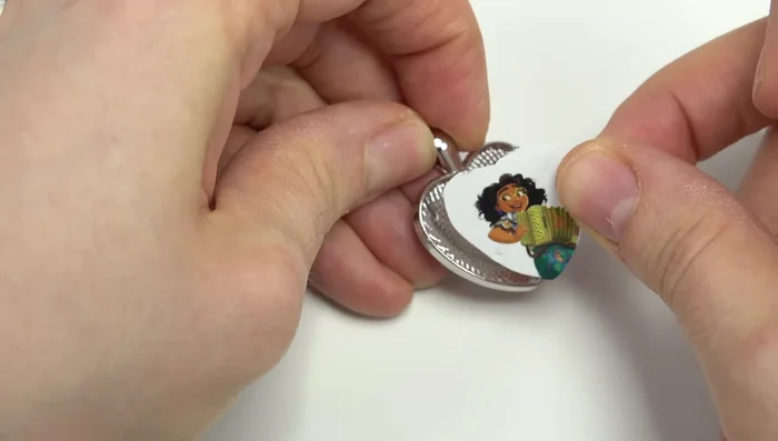 Apply glue to the back of the glass gem and place it on top of the image, pressing gently to secure.