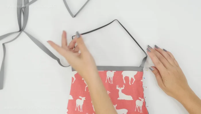 Create neck strap: Fold over and pin the ends of bias tape onto the wrong side of the neck strap area of the apron. Stitch the bias tape into place. 