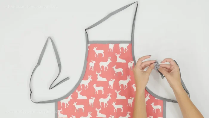 Finish straps and raw edges: Fold over and stitch the raw ends of the waist and neck straps for a neat finish. Stitch along the folded edge of the bias tape to secure the straps.