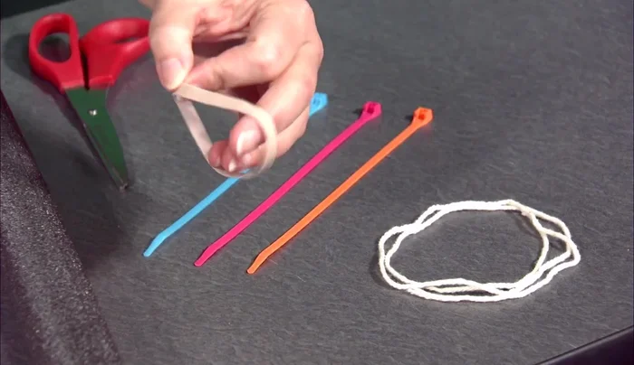 Attach a second zip tie tightly around the nose of the rocket, ensuring the string is pulled down significantly so the rubber band barely protrudes.