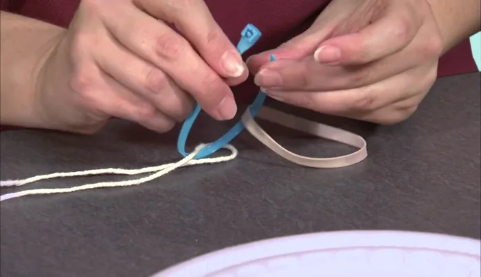 Attach a second zip tie tightly around the nose of the rocket, ensuring the string is pulled down significantly so the rubber band barely protrudes.