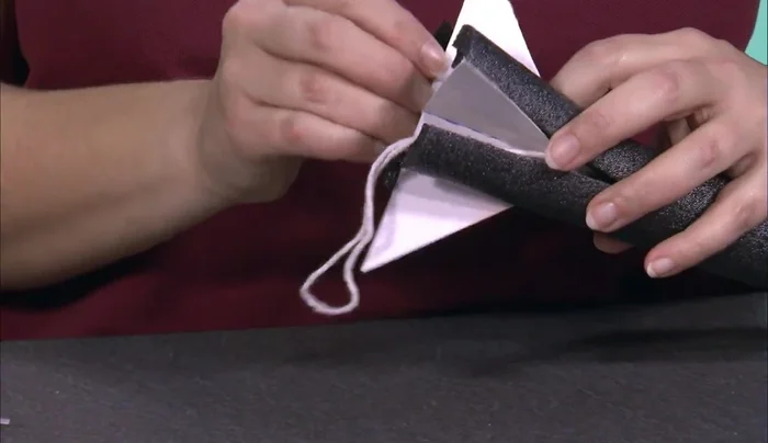 Insert the fins into the flared base of the rocket, ensuring the string is clear, and secure with a third zip tie.