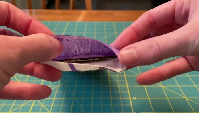 Insert ribbons and sew: Insert ribbons into the top seam, pin, and sew along the top edge to close and secure the ribbons simultaneously. Make sure you’re only sewing through the fabric and not the cardboard.