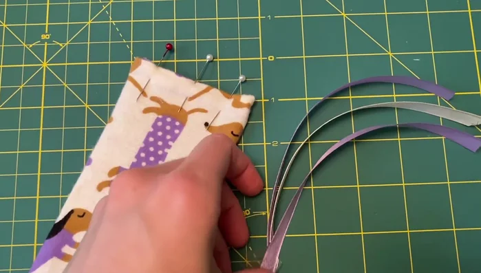 Insert ribbons and sew: Insert ribbons into the top seam, pin, and sew along the top edge to close and secure the ribbons simultaneously. Make sure you’re only sewing through the fabric and not the cardboard.