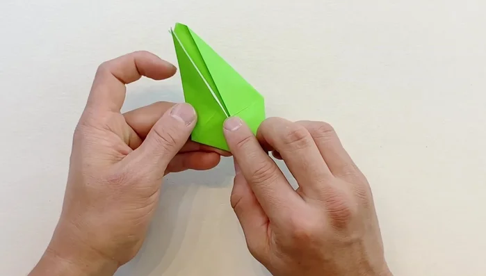 Fold one flap downward to create the front fin. Fold it slightly sideways diagonally, then open and perform a reverse outside fold. Repeat on the opposite side.