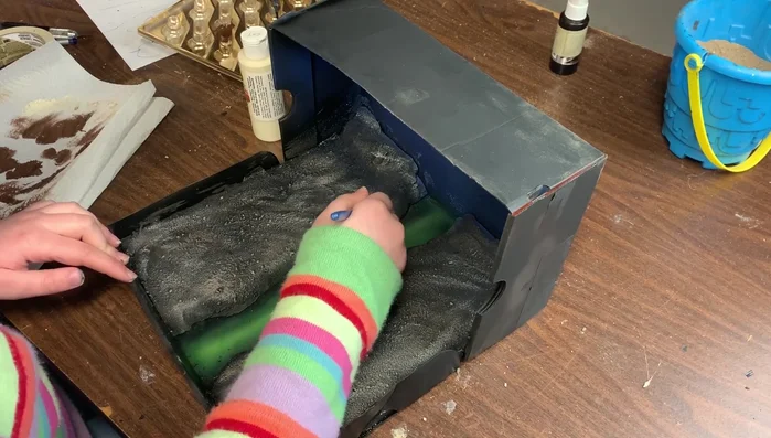 Dry brush earth tone paints onto the land areas to lighten the color and add texture.