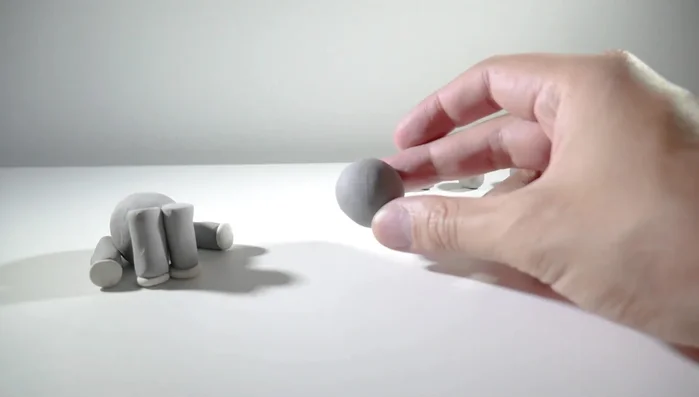 Make two pointed ears from flattened gray clay balls and attach them to the head.