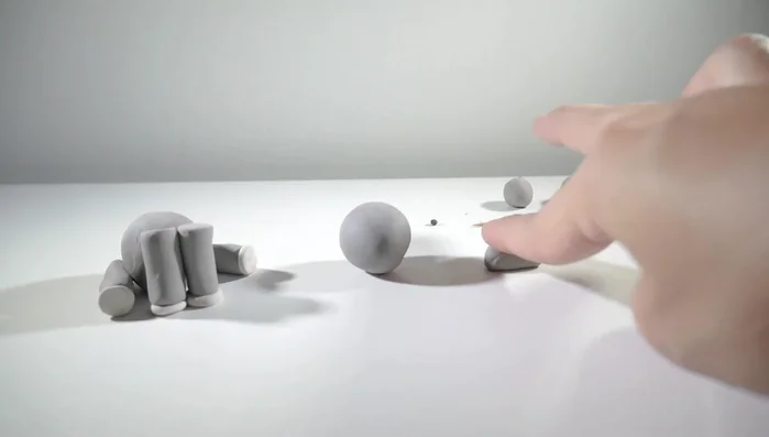 Make two pointed ears from flattened gray clay balls and attach them to the head.