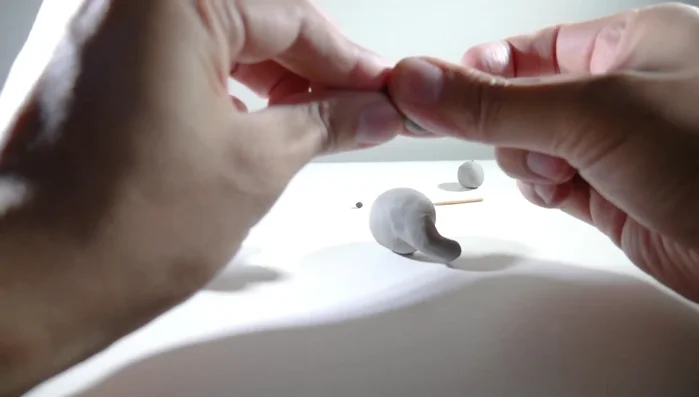 Make two pointed ears from flattened gray clay balls and attach them to the head.