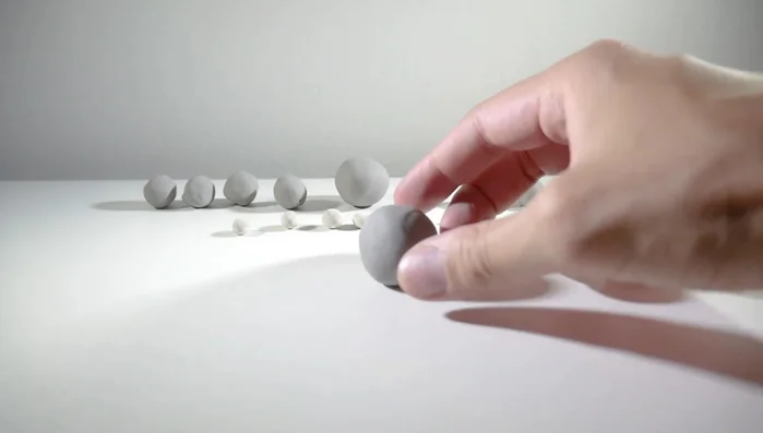 Shape four smaller gray balls into cylinders for legs, same height as the body. Attach them to the body.