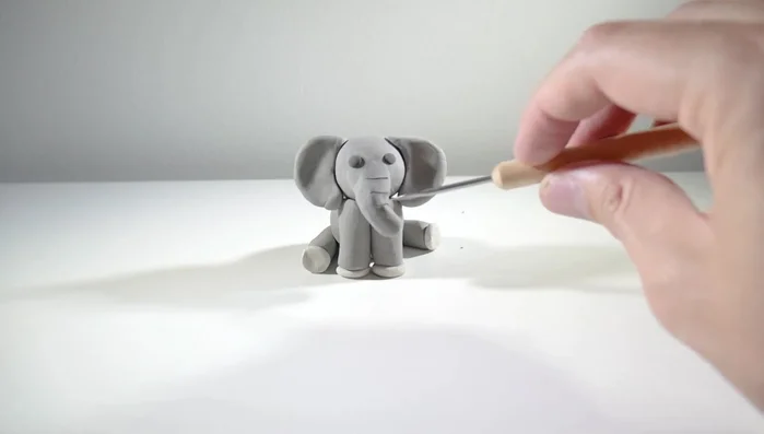 Make a tail from a small gray ball, shape it into a thin strip and attach it to the back.