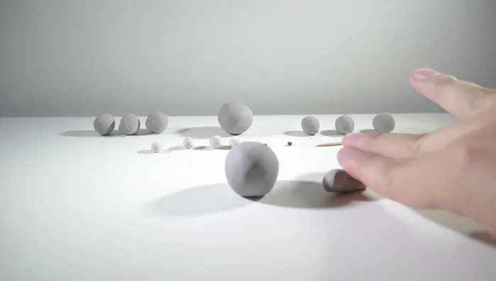 Shape four smaller gray balls into cylinders for legs, same height as the body. Attach them to the body.