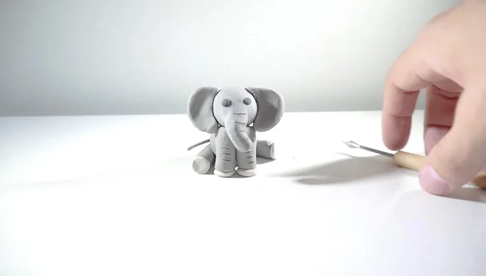 Make a tail from a small gray ball, shape it into a thin strip and attach it to the back.