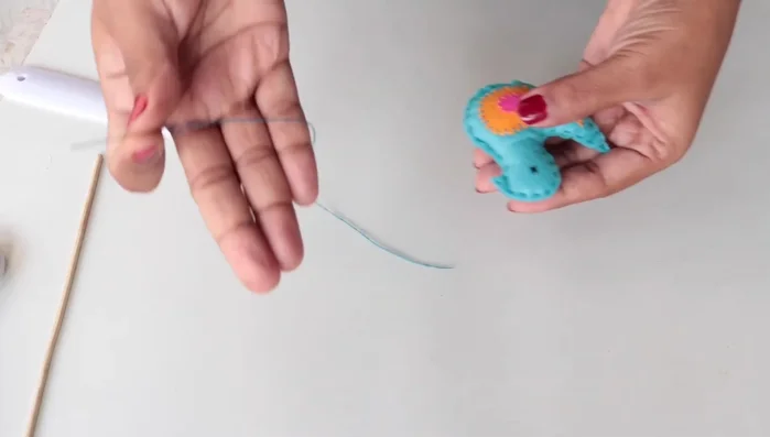 Thread a needle with thread to create a loop for hanging.