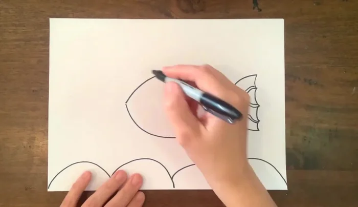 Add details to the fish: draw the face, eye, and additional wavy lines on the body and tail.