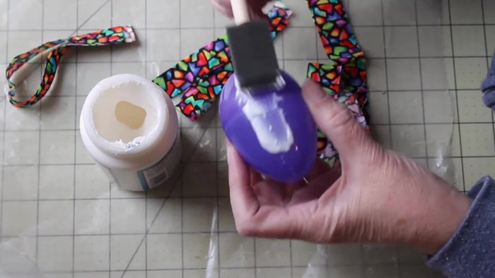 Apply Mod Podge liberally to one section of the plastic egg. A small dot of glue where the egg opens helps keep it closed and prevents shifting.