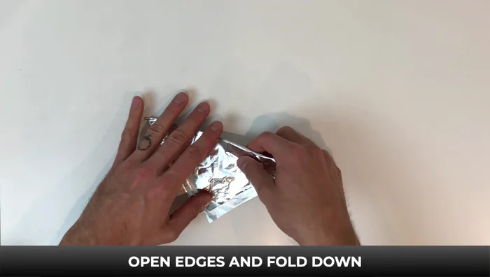 Fold one of the four pieces down to the bottom. Turn it over and fold down the rest to the bottom. Open the edges and fold down. Open it up.