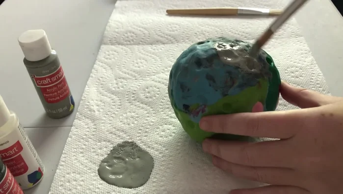 Once the darker gray is dry, mix a lighter gray and lightly brush this over the moon to create highlights and depth.