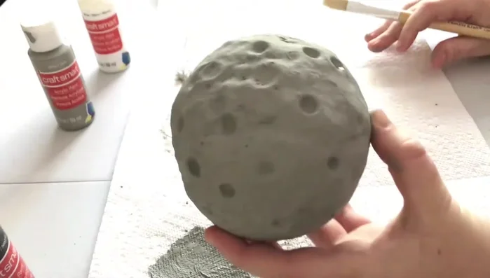 Once the darker gray is dry, mix a lighter gray and lightly brush this over the moon to create highlights and depth.