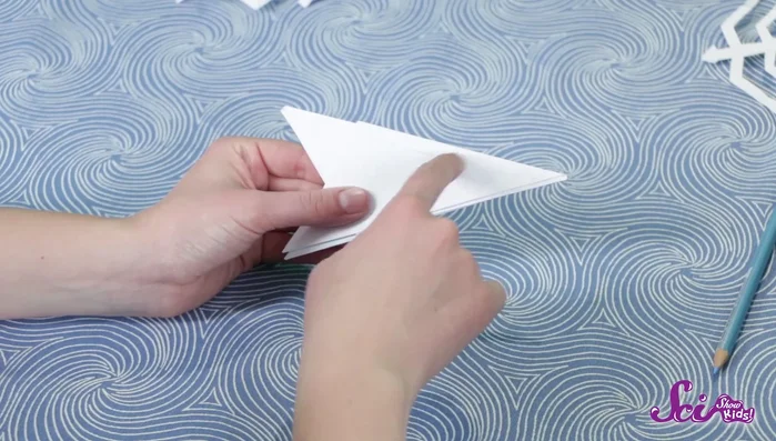 Carefully cut along the pencil lines, making sure not to cut the central fold to maintain the main branches of the snowflake.