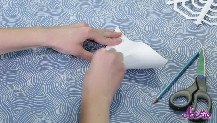 Fold the square paper in half to form a triangle. Then fold it again to create a smaller triangle.