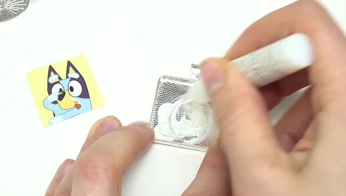 Place the cabochon glass piece over the image, pressing gently to ensure adhesion and remove excess glue with a towel.