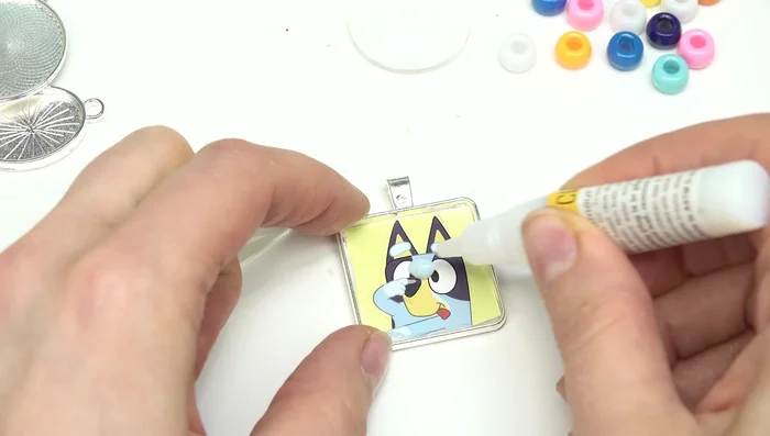 Place the cabochon glass piece over the image, pressing gently to ensure adhesion and remove excess glue with a towel.